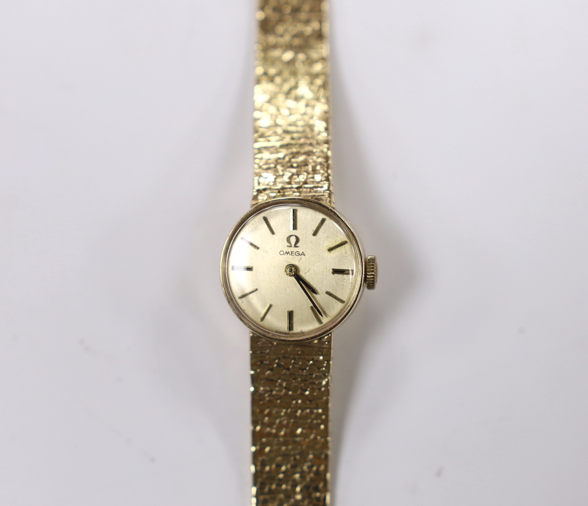 A lady's 9ct gold Omega manual wind wrist watch, on integral 9ct gold bracelet, overall length 15.5cm, gross weight 21.9 grams.